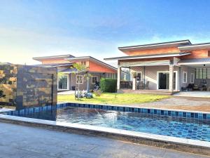 a house with a swimming pool in front of a house at บ้านน้ำผึ้งโฮมสเตย์ Pool & Garden in Suan Phung