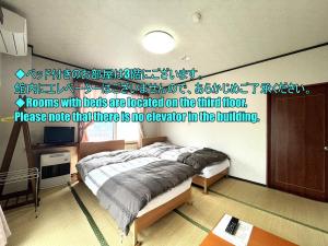 a bedroom with two beds and a sign on the wall at Sunrise Meiji-ya in Nozawa Onsen