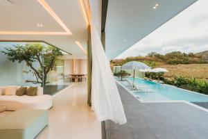 an open living room with a white couch and a pool at Pinepilla Poolvilla Huahin in Hua Hin