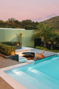 a pool with a bench and a table and a chair at Pinepilla Poolvilla Huahin in Hua Hin