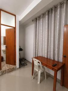 a wooden table and chair in a room with a curtain at Hospedaje Cocos House Talara - amplias habitaciones, Buena Ubicacion in Talara