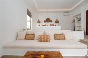 a living room with a white couch with pillows at Villa Camille - Private 1BR Oasis with Pool in Nyanyi Beach in Tanah Lot
