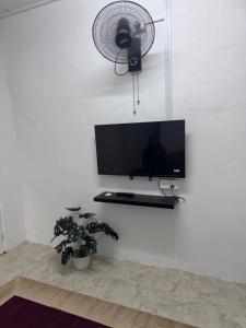 a flat screen tv on a wall with a fan at DNH Nilam Puri Homestay Unit C in Kota Bharu