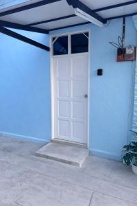 a white door in a blue building with a ceiling at DNH Nilam Puri Homestay Unit C in Kota Bharu +1 photo