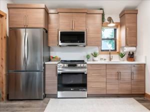 a kitchen with wooden cabinets and a stainless steel refrigerator at Alpenhaus | Ski Jackson & Targhee in Victor +26 photos