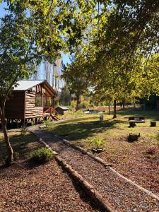 a log cabin in a park with a tree at Refugio El Rocio lodge tinaja,piscina,bosque in Nacimiento