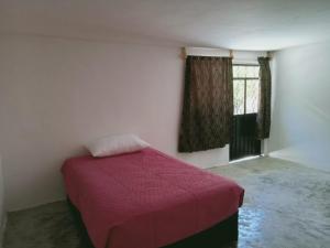 a bedroom with a bed with a red blanket and a window at Habitación cerca del centro de Tlaxcala in Ocotlán