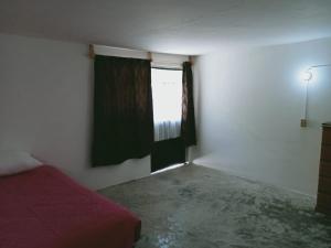 a bedroom with a red bed and a window at Habitación cerca del centro de Tlaxcala in Ocotlán