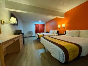 two beds in a hotel room with orange walls at Hermiston Inn & Suites in Hermiston