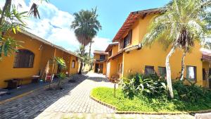a yellow building with palm trees and a sidewalk at Chalés Água de Coco in Boicucanga +15 photos