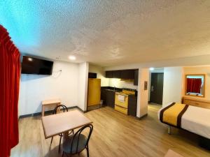 a room with a bed and a table and a kitchen at Hermiston Inn & Suites in Hermiston
