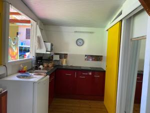 a kitchen with red cabinets and a clock on the wall at Maison créole in Lamentin +2 photos