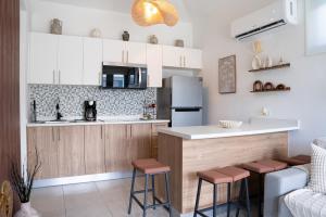 a kitchen with white cabinets and a bar with stools at Villa Lua, Boqueron, Puerto Rico in Cabo Rojo