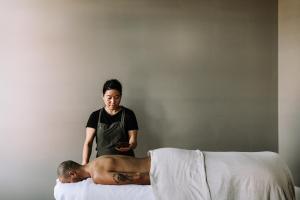 a woman standing next to a man laying on a bed at The Benev - Wellness Accommodation in Beechworth
