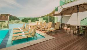 a swimming pool with chairs and tables and an umbrella at Sant copacabana in Rio de Janeiro