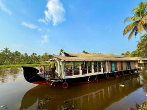 a house boat on a river with a man on it at Grand Villa Houseboat in Kumarakom