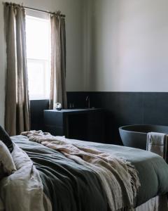 a bedroom with a bed and a tub and a window at The Benev - Wellness Accommodation in Beechworth