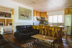 a living room with a black leather couch and a table at Monzi Safari Lodge in Monzi