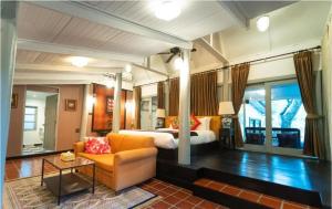 a bedroom with a bed and a couch and a chair at Zantiis Ndol Villas in Muak Lek District
