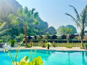 a pool with palm trees and mountains in the background at Cham Trang An Retreat in Vũ Lâm