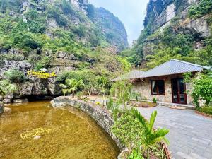 a building next to a river with a mountain at Cham Trang An Retreat in Vũ Lâm