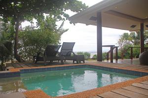 a swimming pool with two chairs next to a house at Baha Bar in San Juan
