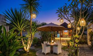 a table and chairs with an umbrella and palm trees at Svaha Private Villas Ceningan in Nusa Lembongan