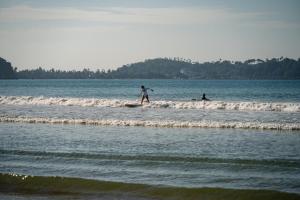 two people are walking in the waves in the ocean at Southbeach Weligama in Weligama +43 photos