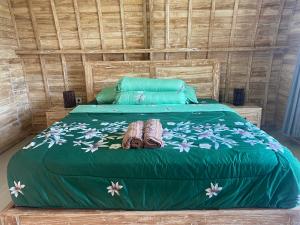 a bed with a green comforter and two shoes at Sari Lumbung Bungalow in Penginuman