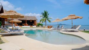 a swimming pool with chairs and umbrellas and the ocean at Azul Beach Resort in Bophut