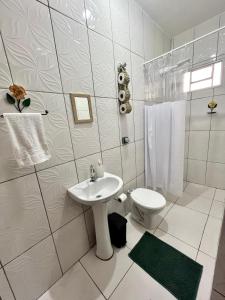 a white bathroom with a sink and a toilet at A Casa di Minas in Três Corações