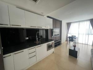 a kitchen with white cabinets and a black counter top at Central Pattaya Apartments in Pattaya