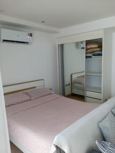 a white bedroom with a bed and a mirror at Central Pattaya Apartments in Pattaya +69 photos