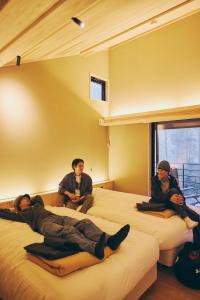 three men sitting on beds in a room at GEOSPOT Motohakone C 2026年1月 New Open in Hakone