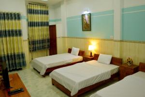 a hotel room with two beds and a television at Vien Duong Hotel in Quy Nhon +4 photos