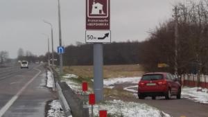 a red car parked on the side of a road with a sign at Agrousadby Veronika in Borisovo