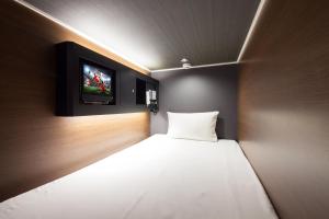 a hotel room with a bed and a television at commun SHIBUYA (Male Only) in Tokyo