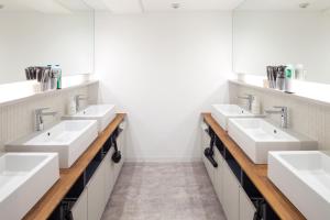 a bathroom with four sinks and a row of mirrors at commun SHIBUYA (Male Only) in Tokyo