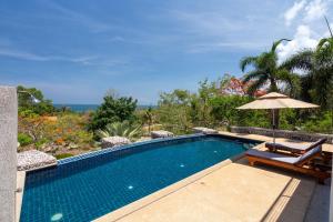 a swimming pool with an umbrella and two chairs at Amazing Seaview Apartment in Ko Lanta