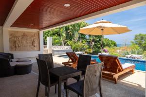 a patio with a table and chairs and an umbrella at Amazing Seaview Apartment in Ko Lanta