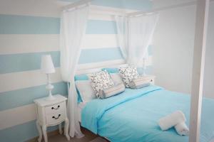 Un dormitorio con una cama azul con almohadas y una ventana en Kantra Residence, en Xlendi
