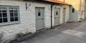 a stone building with three garage doors on it at Drewe Arms Bunk Rooms in Drewsteignton