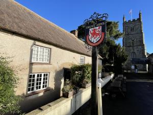 a sign in front of a building with a church at Drewe Arms Bunk Rooms in Drewsteignton