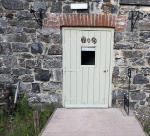 a white door in a brick wall with two bicycles at Drewe Arms Bunk Rooms in Drewsteignton