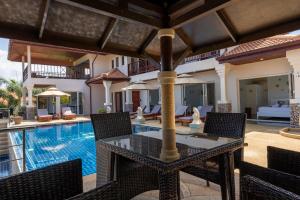 a patio with a table and chairs next to a swimming pool at Amazing Seaview Villa Serena 4 Bedrooms in Ko Lanta