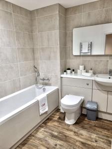 a bathroom with a tub and a toilet and a sink at Comfortable modern apartment near Bicester in Bicester +16 photos