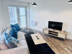 a living room with a couch and a flat screen tv at Comfortable modern apartment near Bicester in Bicester