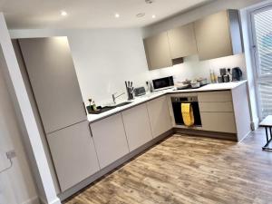 a kitchen with white cabinets and a wooden floor at Comfortable modern apartment near Bicester in Bicester