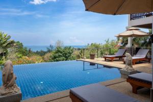 a swimming pool with two chairs and an umbrella at 2 Pools And Seaview! Villa Serena 6Br, Klong Khong in Ko Lanta