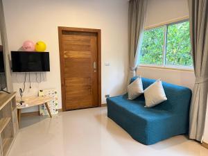 a living room with a blue couch and a wooden door at Blue Sky Condo by Palmetto Karon in Ka Rorn
